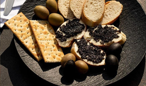 caviar and crackers on a plate with olives